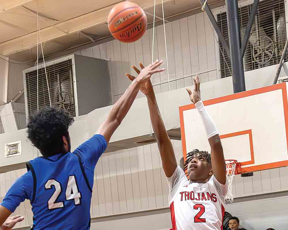 Tristen Cullum jumps over Kelvin Harden for a layup during the district game on Wednesday night. Photo by Charles Ballard