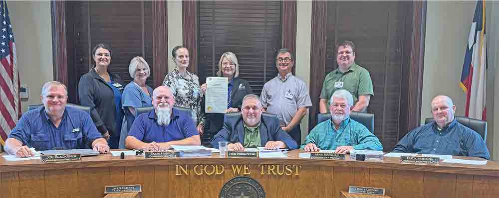 Standing, left-to-right: Connie Sturrock; Connie Gibson; Christina Hood; Sondra Williams; Scott McCluskey and James Stephens accept a proclamation from the county, recognizing National Hospital Week. Seated, left-to-right: Pct. 1 Commissioner Joe Blacksher; Pct. 2 Commissioner Doug Hughes; County Judge Milton Powers; Pct. 3 Commissioner Mike Marshall and Pct. 4 Commissioner Buck Hudson.