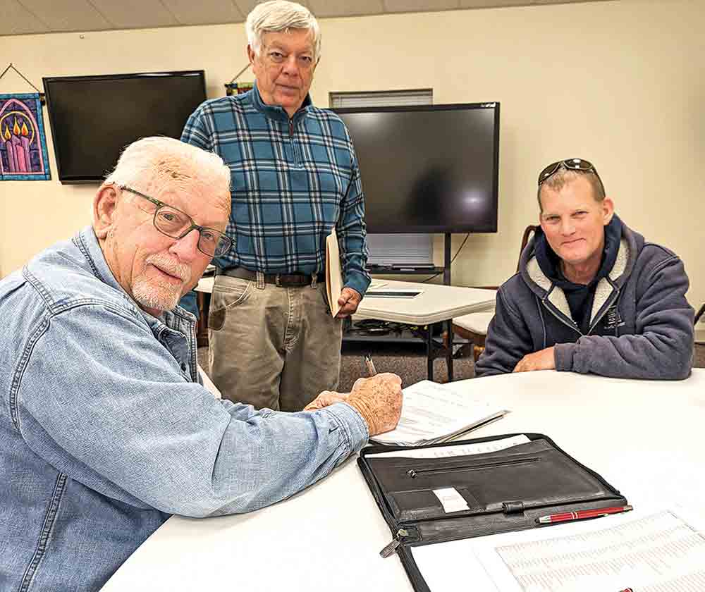 Mike Bischoff of “The Happy Hookers” Lake Livingston Fishing Club signs a permit application as Ron Diderich, president of Friends of Lake Livingston, and Dan Ashe, an inland fisheries biologist with Texas Parks and Wildlife Department, look on. The three men and the groups they represent are part of a larger effort to stock Lake Livingston with hybrid bass, making it a destination lake for anglers. Courtesy photo