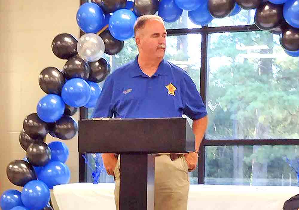 Police Chief Clint Headley listens to Sheriff Greg Capers at the swearing-in ceremony in Shepherd.